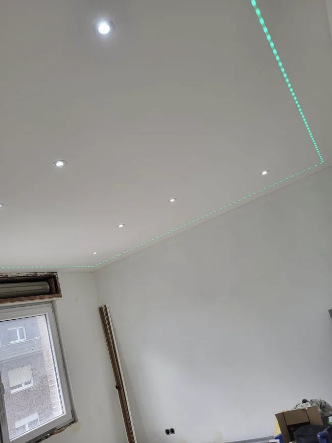 Interior ceiling with recessed lights and cyan LED strip lighting along the corners, with a window and door frame visible below