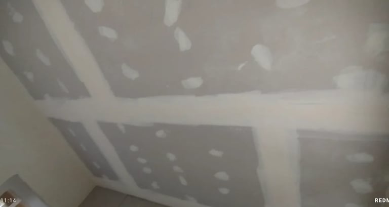 Drywall ceiling with recessed light fixtures and white joint tape during interior construction